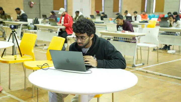 A laptop from over a player's shoulder, a dark terminal filling the screen