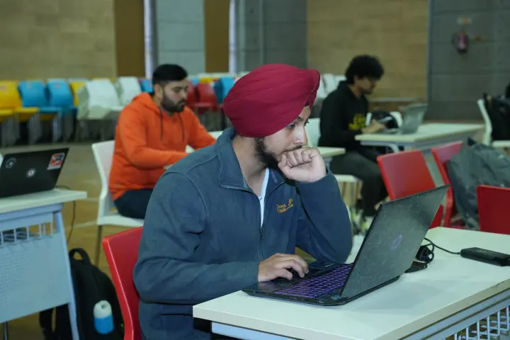 Two players sharing a desk, one laptop open on a terminal